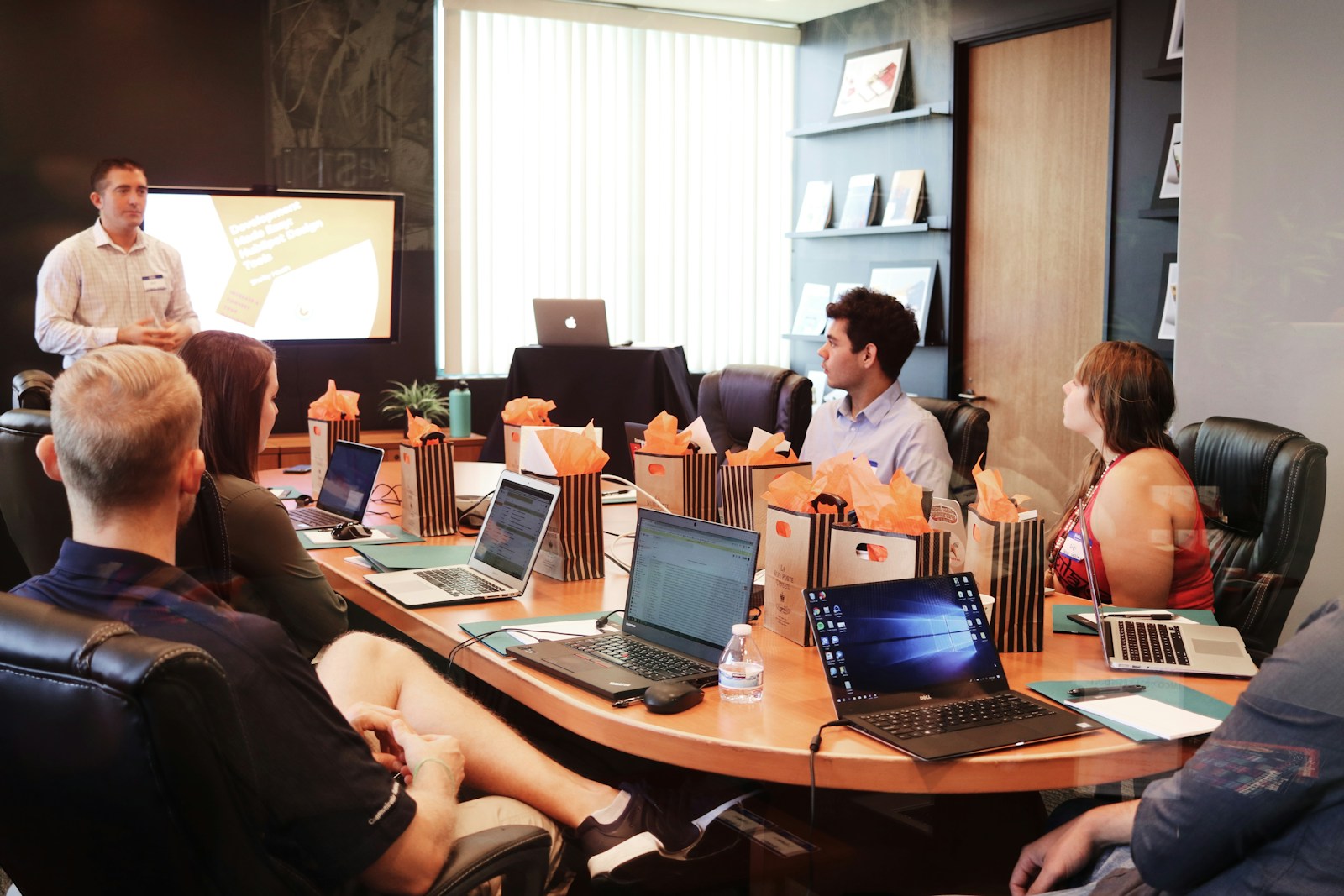 business, man standing in front of people sitting beside table with laptop computers